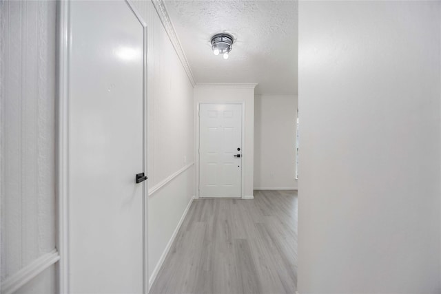 hallway featuring ornamental molding, a textured ceiling, and light hardwood / wood-style flooring