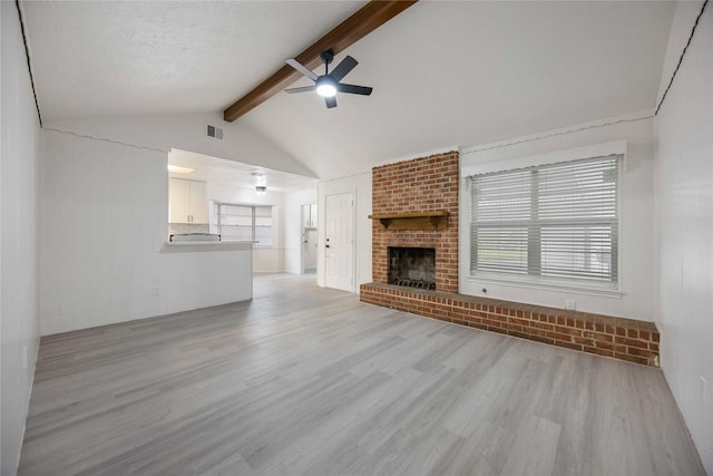 unfurnished living room featuring ceiling fan, vaulted ceiling with beams, light hardwood / wood-style floors, a textured ceiling, and a fireplace