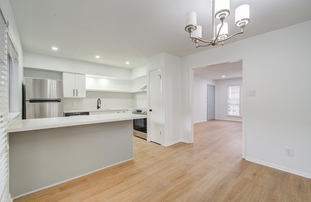 kitchen with appliances with stainless steel finishes, sink, decorative light fixtures, a notable chandelier, and white cabinetry