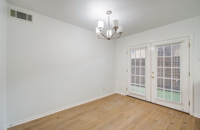 spare room with light wood-type flooring and a notable chandelier