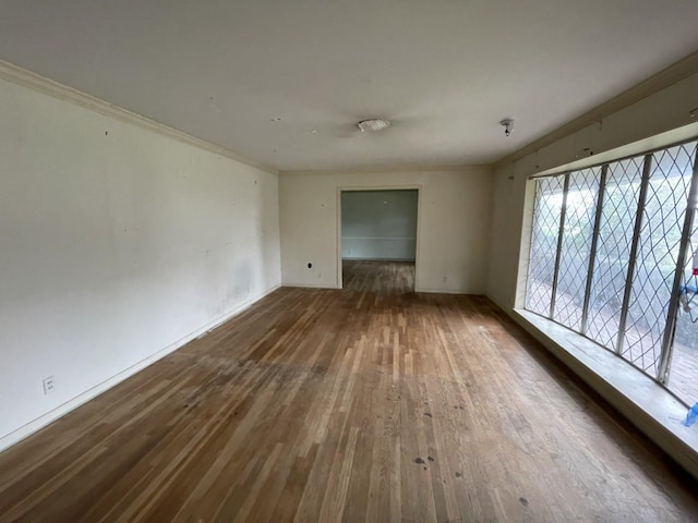 empty room with hardwood / wood-style flooring and crown molding