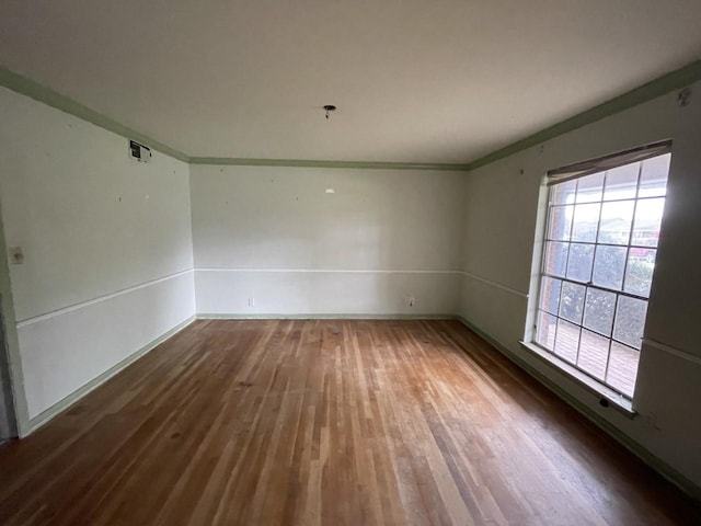 empty room featuring dark wood-type flooring and ornamental molding