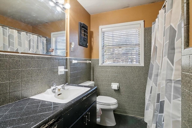 bathroom with vanity, a healthy amount of sunlight, toilet, and tile walls