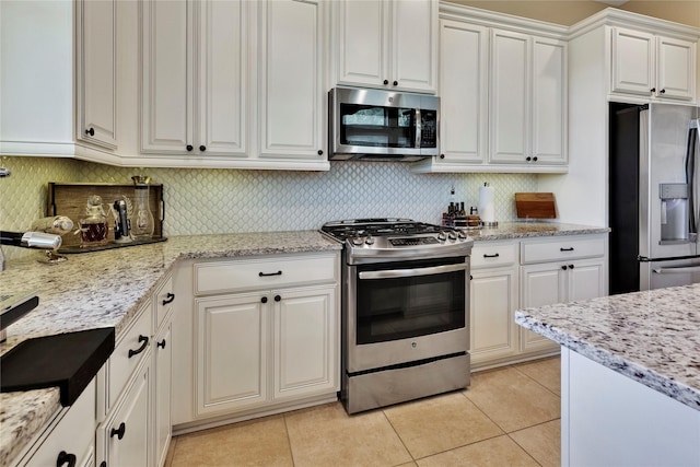 kitchen featuring backsplash, white cabinetry, stainless steel appliances, and light tile patterned floors