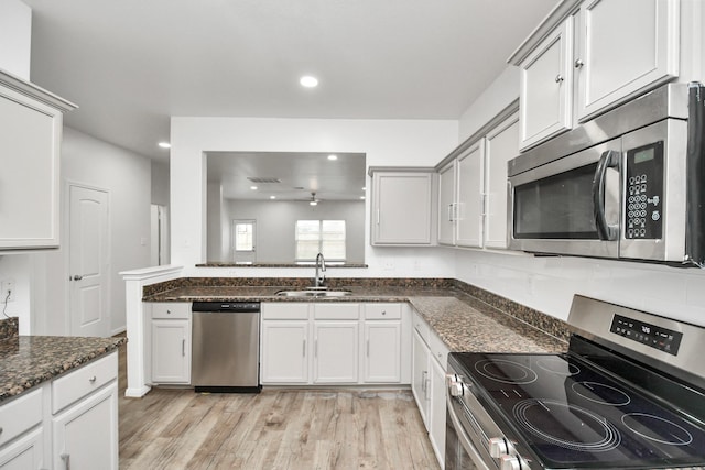 kitchen featuring dark stone countertops, sink, light hardwood / wood-style floors, and appliances with stainless steel finishes