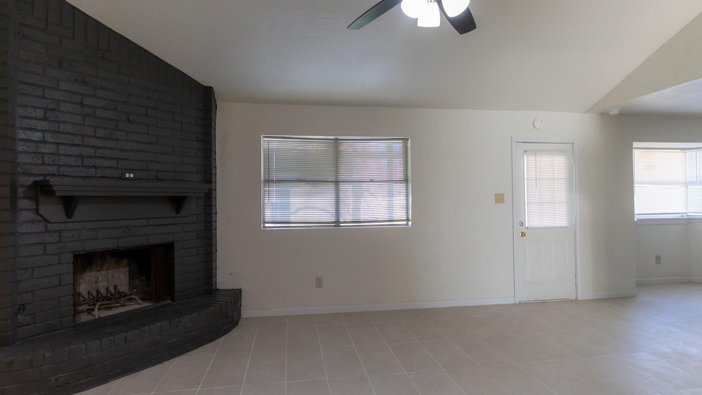 unfurnished living room with a fireplace, light tile patterned floors, vaulted ceiling, and ceiling fan