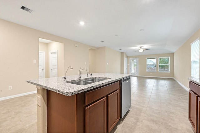 kitchen with dishwasher, a kitchen island with sink, sink, ceiling fan, and light stone countertops