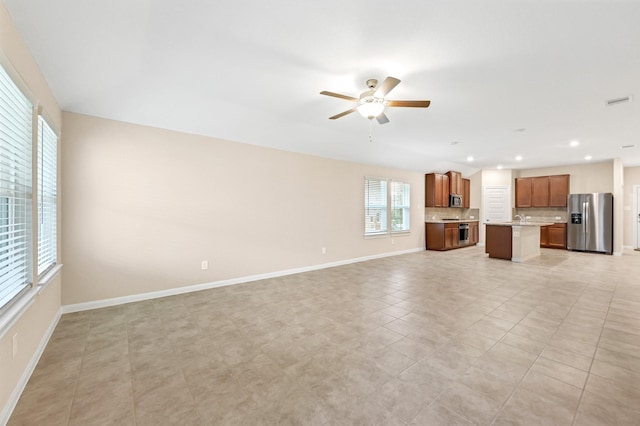 unfurnished living room featuring light tile patterned floors and ceiling fan