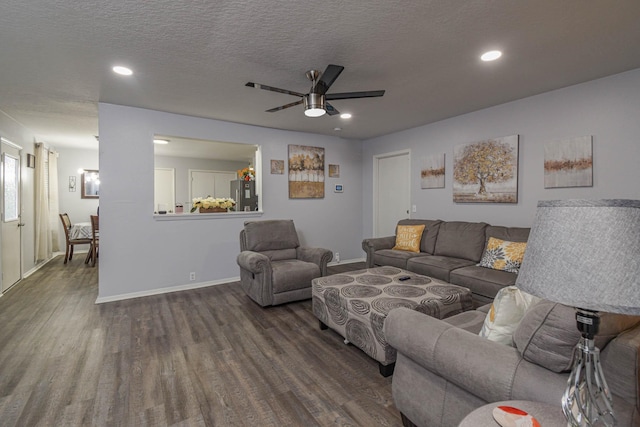 living room featuring dark hardwood / wood-style flooring, a textured ceiling, and ceiling fan