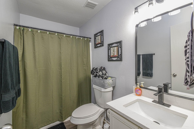 bathroom with a textured ceiling, hardwood / wood-style flooring, vanity, and toilet