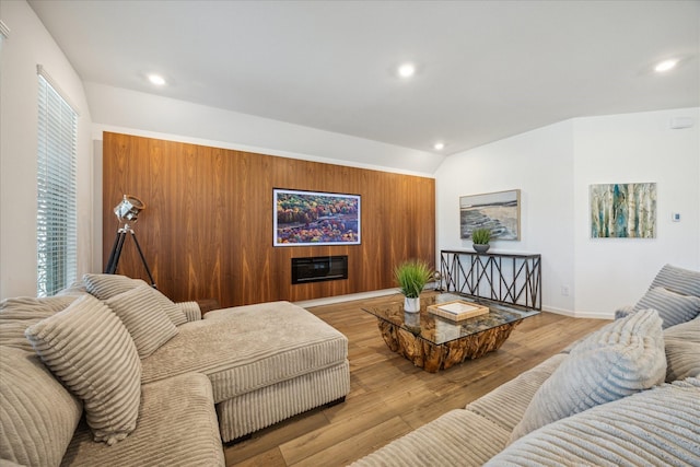 living room featuring wooden walls, light hardwood / wood-style floors, and lofted ceiling