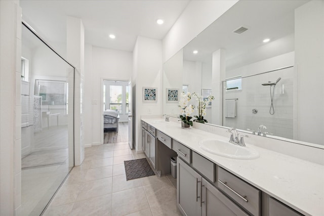 bathroom with tile patterned flooring, vanity, and tiled shower