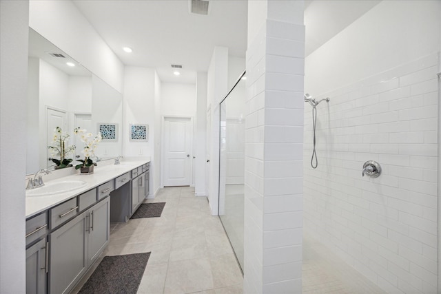 bathroom with tiled shower, a high ceiling, vanity, and tile patterned floors