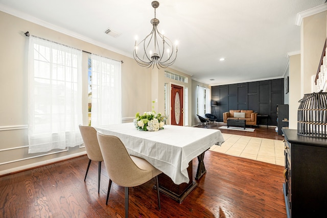 dining space featuring crown molding, an inviting chandelier, and hardwood / wood-style floors