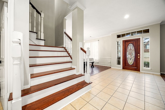 entryway with light tile patterned floors, ornamental molding, and stairs