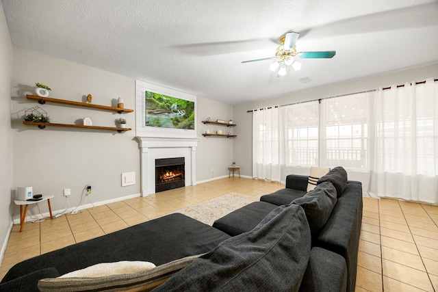 tiled living room with ceiling fan, a textured ceiling, and a fireplace