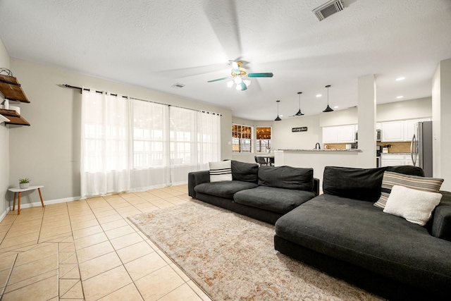 tiled living room featuring ceiling fan and a textured ceiling