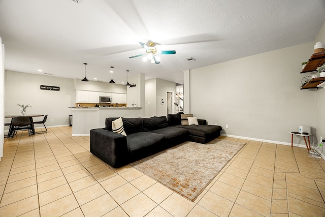 tiled living room featuring a textured ceiling and ceiling fan