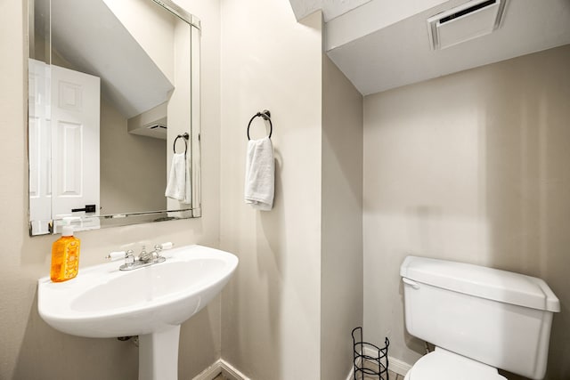 half bathroom featuring baseboards, visible vents, a sink, and toilet