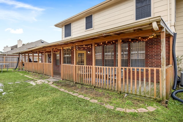 back of house with a yard, brick siding, and fence