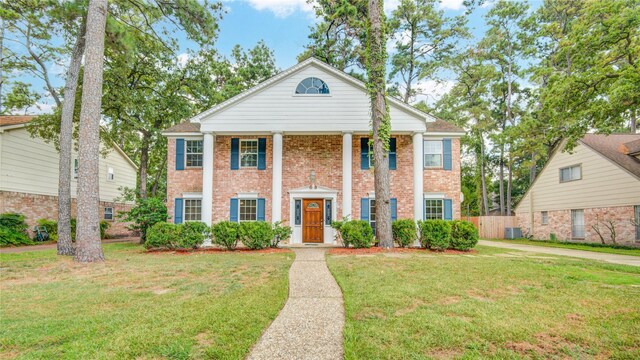 greek revival inspired property with a front yard and central AC unit