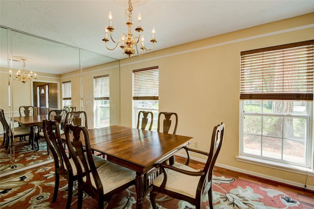 dining space with an inviting chandelier, wood-type flooring, and a wealth of natural light