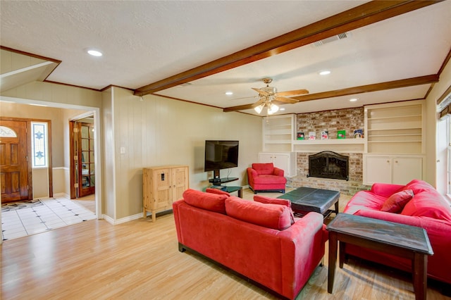 living room with built in shelves, ceiling fan, light hardwood / wood-style floors, and a brick fireplace