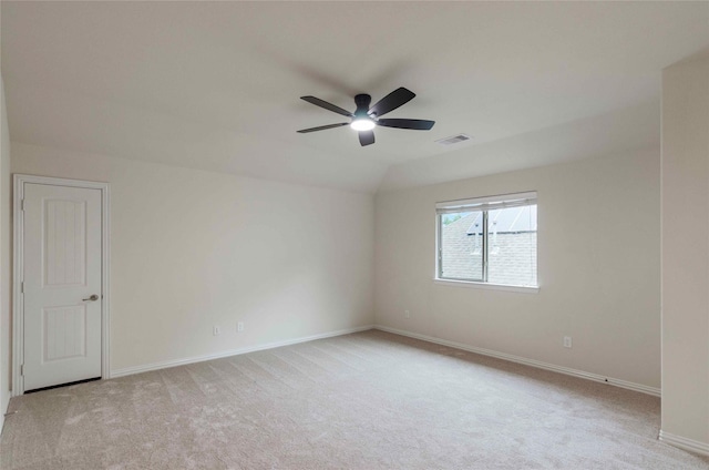 spare room featuring ceiling fan, light carpet, and vaulted ceiling