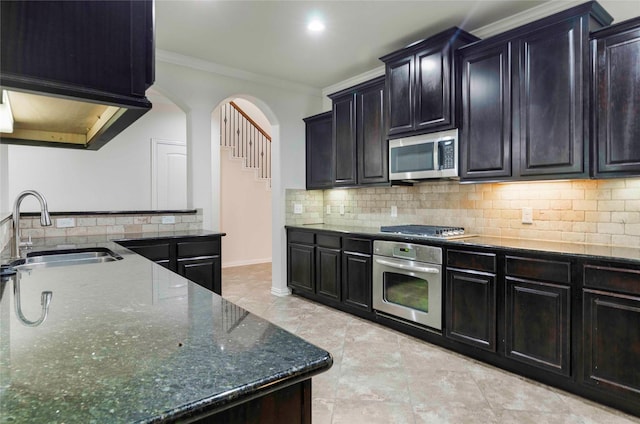 kitchen with sink, dark stone countertops, ornamental molding, tasteful backsplash, and stainless steel appliances