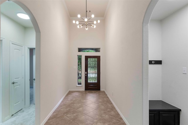 tiled entrance foyer featuring an inviting chandelier and ornamental molding