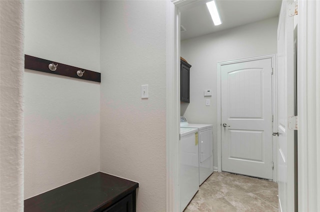 clothes washing area with separate washer and dryer and cabinets