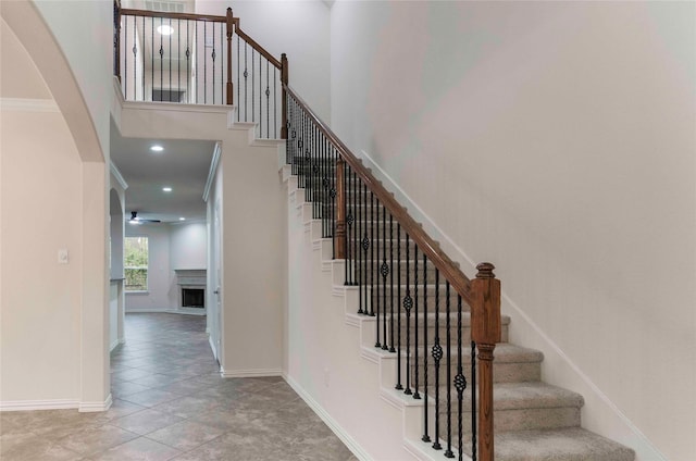 stairs with tile patterned floors, ceiling fan, and crown molding