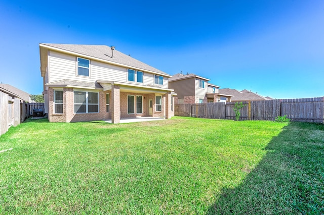 rear view of house featuring a lawn and a patio