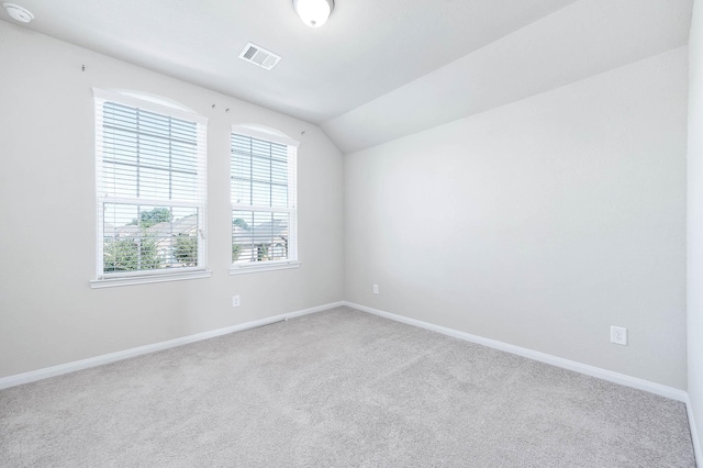 carpeted empty room with vaulted ceiling