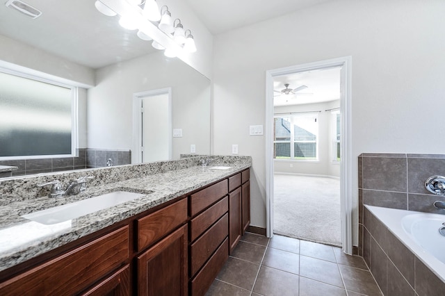 bathroom with tile patterned flooring, vanity, a relaxing tiled tub, and ceiling fan