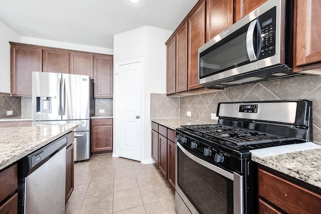 kitchen featuring light stone counters, light tile patterned floors, appliances with stainless steel finishes, and tasteful backsplash