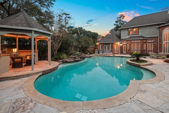 pool at dusk featuring a gazebo, area for grilling, a patio, and grilling area