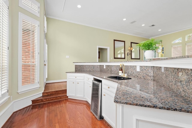 kitchen with white cabinetry, sink, stone counters, wine cooler, and decorative backsplash