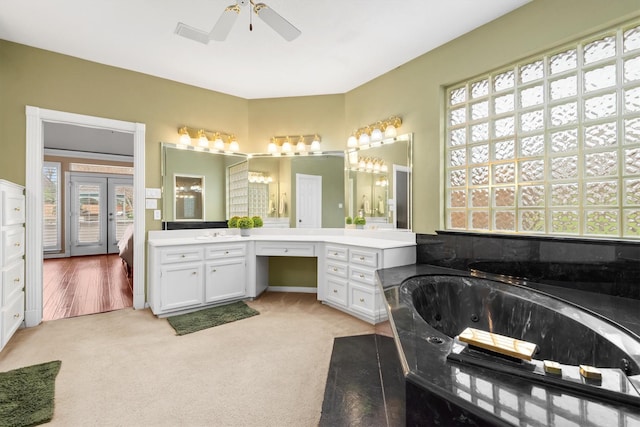 bathroom featuring vanity, ceiling fan, tiled tub, and french doors