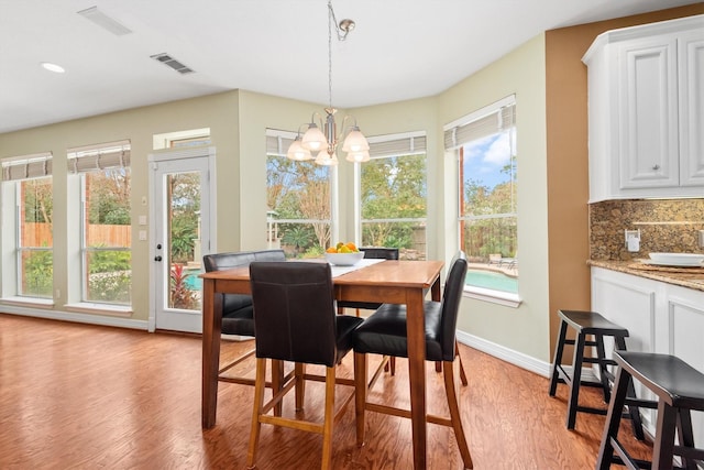 dining area with a notable chandelier, a wealth of natural light, and light hardwood / wood-style flooring