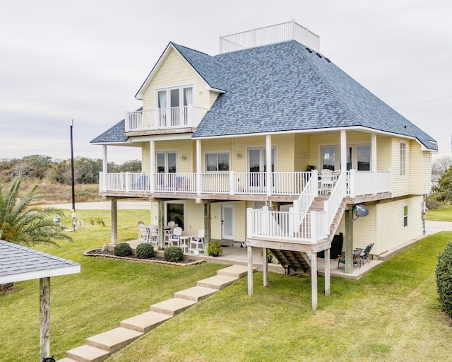 back of house featuring a lawn, a balcony, and a patio