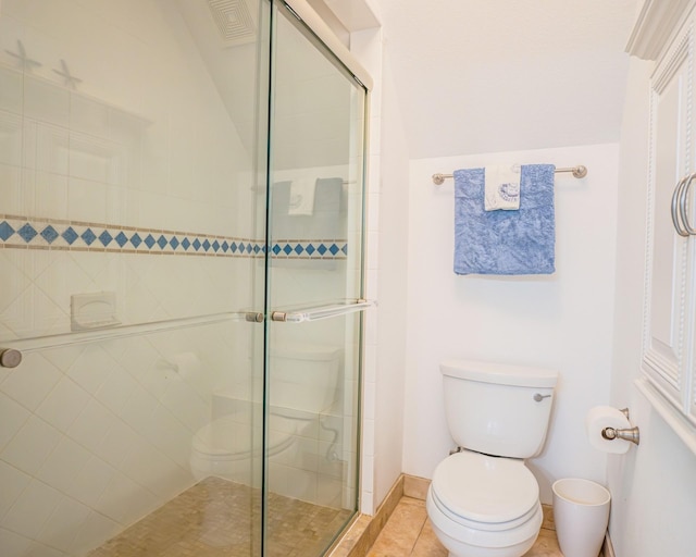 bathroom featuring tile patterned floors, toilet, and a shower with door