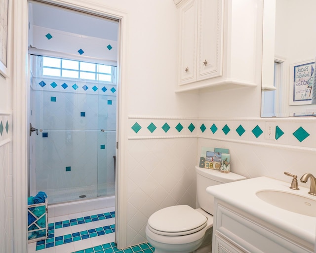 bathroom featuring toilet, tile patterned flooring, tile walls, walk in shower, and vanity