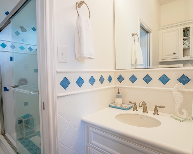 bathroom with vanity, tile walls, and a shower with door