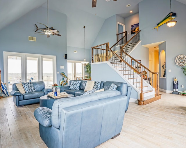 living room featuring light hardwood / wood-style floors, plenty of natural light, ceiling fan, and a towering ceiling