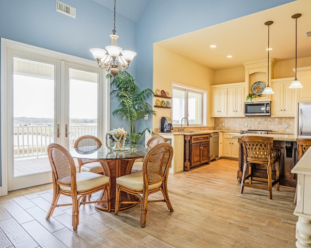 dining room featuring light hardwood / wood-style floors, sink, lofted ceiling, and a chandelier