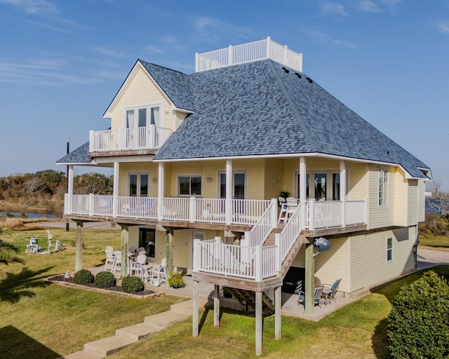 rear view of house with a balcony, a yard, and a patio