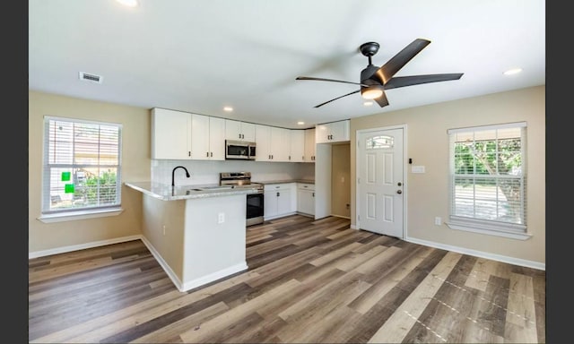 kitchen featuring white cabinets, plenty of natural light, kitchen peninsula, and stainless steel appliances