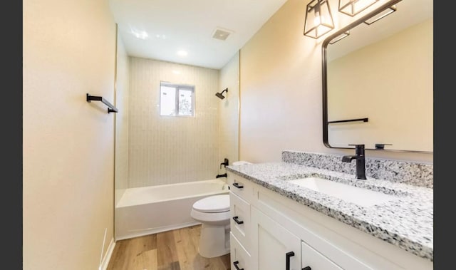 full bathroom featuring vanity, hardwood / wood-style floors, tiled shower / bath combo, and toilet