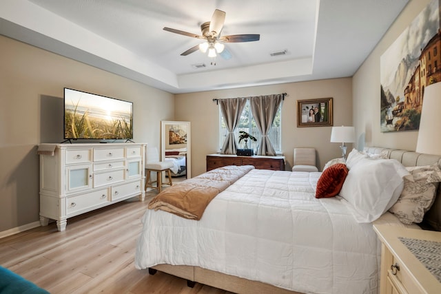 bedroom featuring a tray ceiling, ceiling fan, and light hardwood / wood-style floors